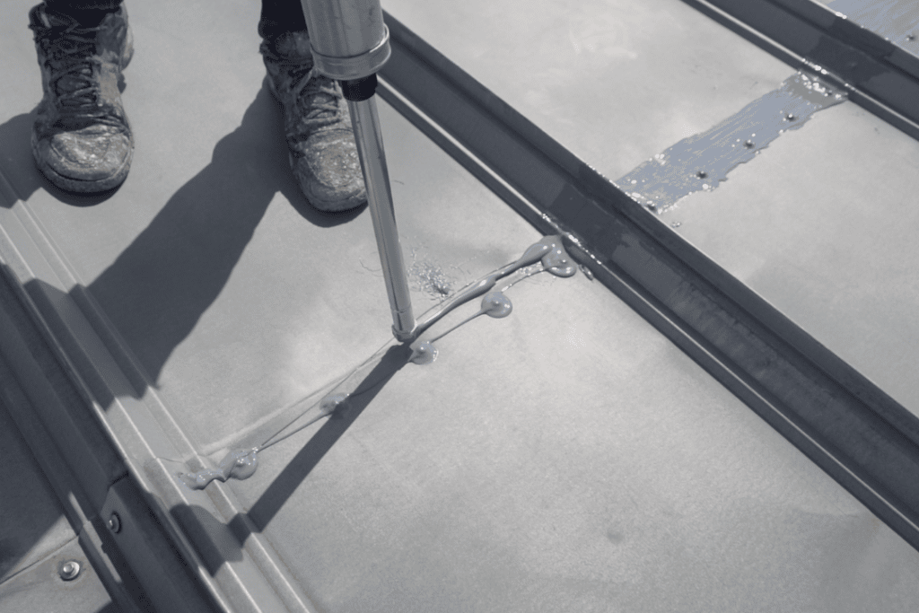water proofing a commercial flat metal roof during the process of leak repair.