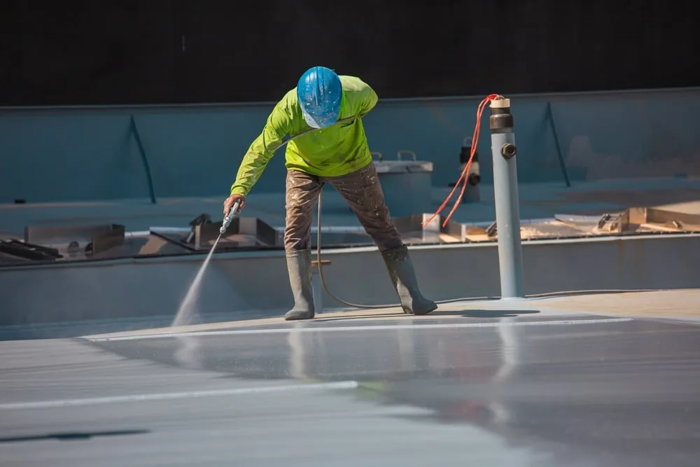 Commercial roofing company pressure washing a flat roof sytem.